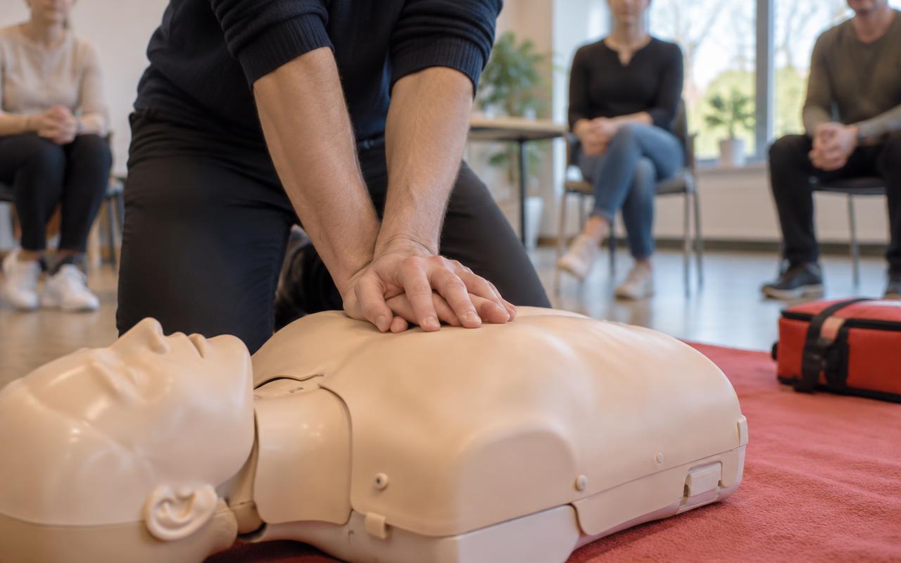 Händer som övar hjärtkompressioner på en trainingsdocka under en HLR-utbildning.